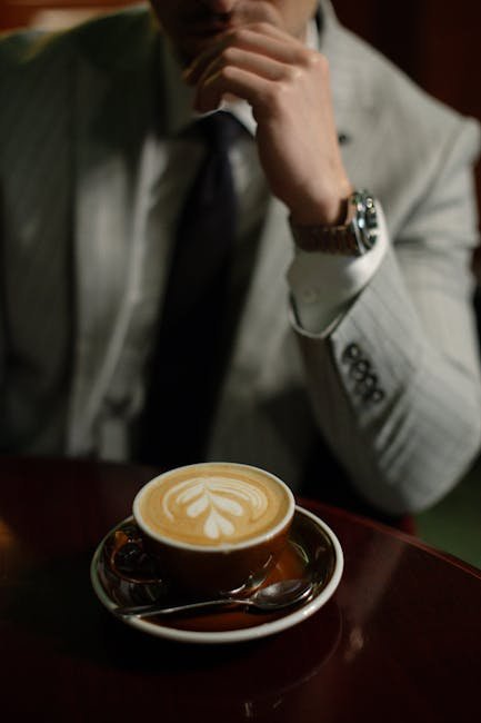 A stylish man in a suit enjoys a latte with art in a Slovakian cafe.